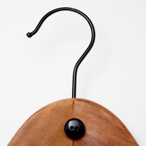 Closeup of the top of a wooden coat hanger with metal hook in the shape of a question mark with a button for the dot