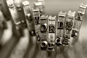 Monochrome image of typebars on an old typewriter that spell "words" in both uppercase and lowercase.