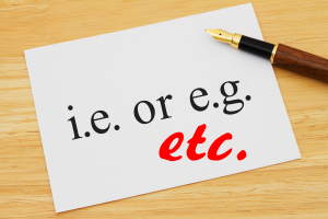 Pen on paper reading "i.e. or e.g." with "etc." drawn in red below.