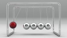 A Newton's cradle featuring four silver balls and one red ball. The silver balls are at rest, touching each other. The red ball is suspended in mid-swing to their left.