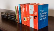 The 1st through 17th editions of the Manual of Style, minus the 6th edition, lined up on a desk.